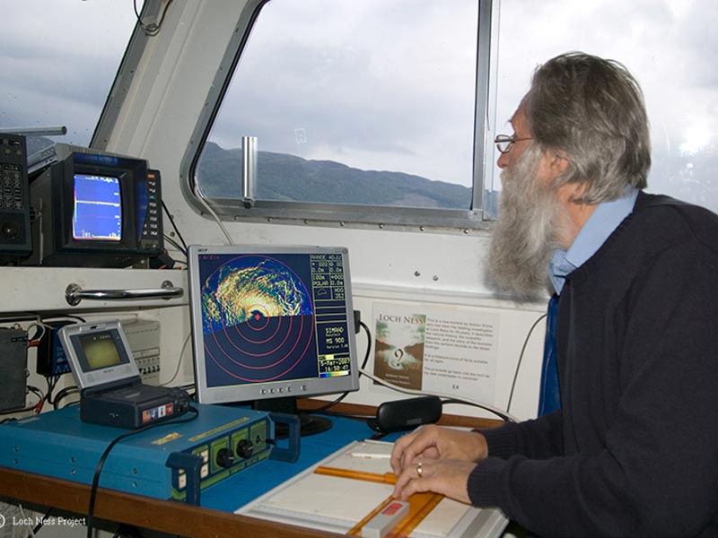 Photo of an older white man on a boat using a variety of monster-hunting equipment.