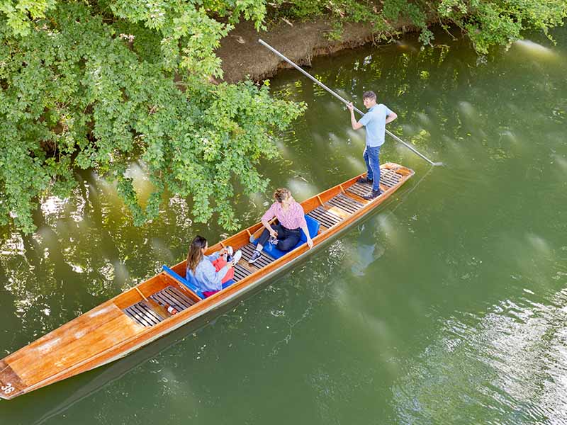 Two women enjoying chauffered punting on the river Cherwell at Cherwell Boathouse in Oxford