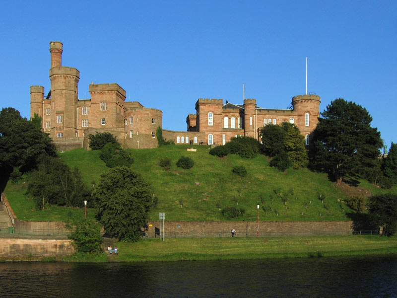 A photo of Inverness Castle from the other side of the River Ness on a bright blue day